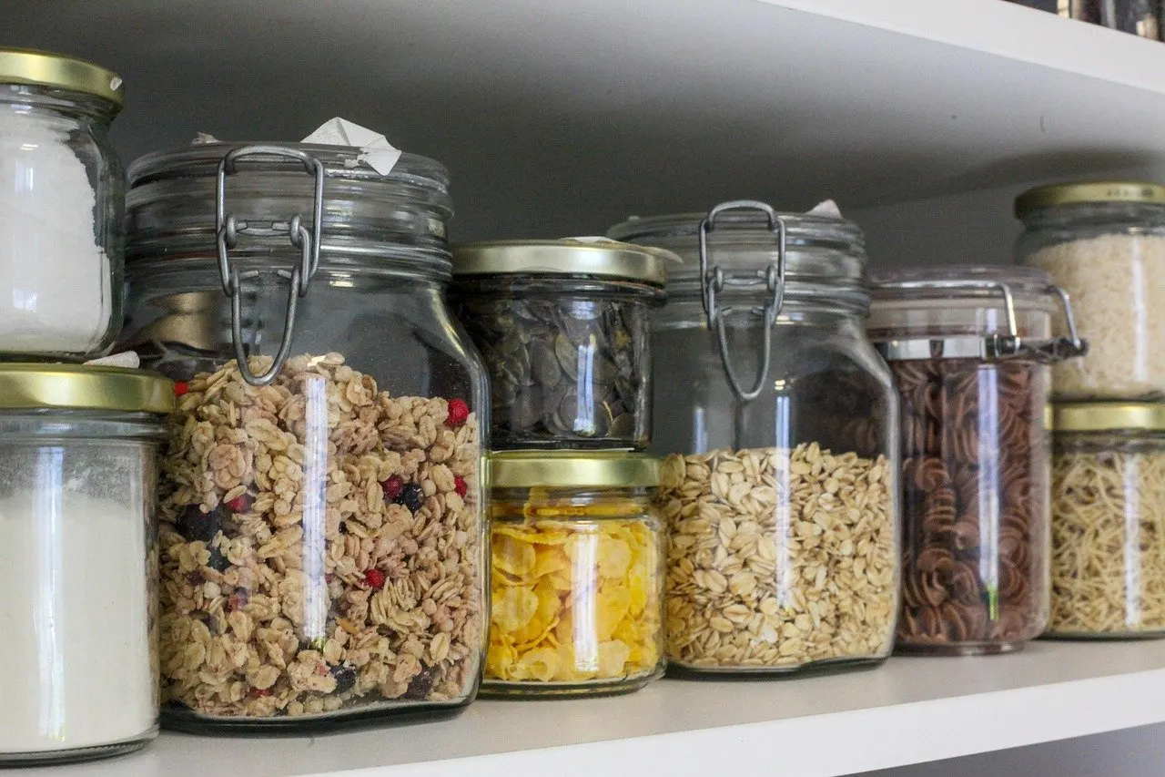 Regalboden mit Bügelgläsern und Schraubgläsern voller Müsli, Haferflocken, Nudeln, Cornflakes und Mehl